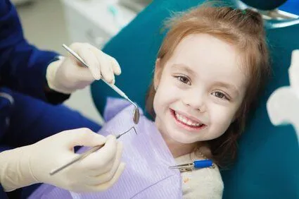 little girl wearing dental bib getting dental exam done, family dentist Zebulon, NC