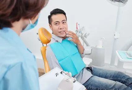 man talking to dentist holding his mouth in pain, needs root canals Plantation, FL dentist