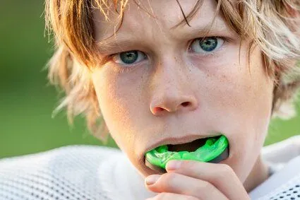 boy in football uniform placing mouth guard in his mouth, dentist Wauwatosa, WI family dentistry