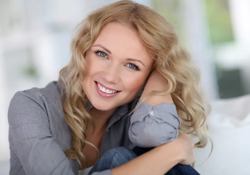 blond woman smiling nice teeth, leaning head on hand, dental crowns and dental bridge Salem, OR dentist