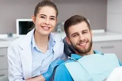 female dentist next to man smiling in dentist chair, Lee's Summit, MO teeth cleaning