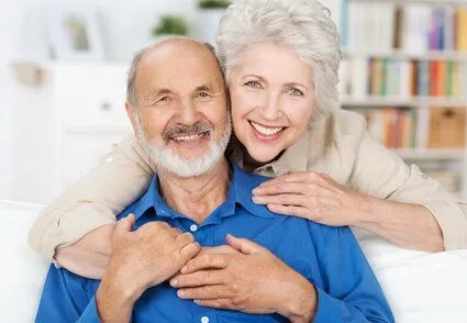 older woman embracing older man and smiling nice teeth, dentures Roslyn, NY dentist