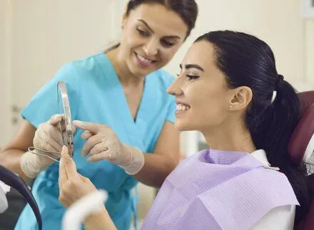 dentist showing female patient teeth in handheld mirror, dentist Old Bridge, NJ family dentist