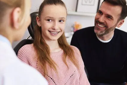 orthodontist talking with teen girl that has braces and her dad, orthodontist for children Milford, MI