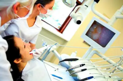 dental assistant performing digital x-ray of female patient's mouth, family dentist Columbia, MO 