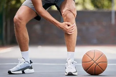 man with knee pain from basketball