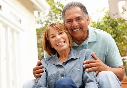 older Hispanic couple smiling hugging outdoors, dentures San Diego, CA dentist