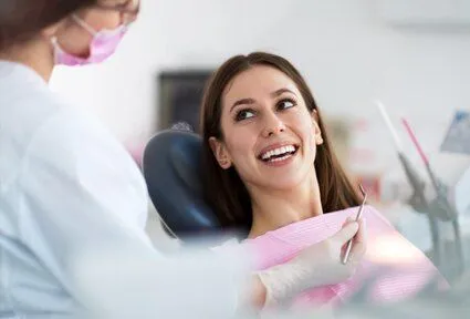 dentist talking to smiling female patient in exam chair, dental bridge Seminole, FL dentist