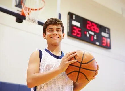 boy standing on basketball court holding basketball, custom athletic mouthguards Old Bridge, NJ dentist 08857