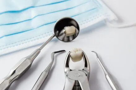 assortment of dental tools on white counter with extracted tooth, family dentist Durham, NC cosmetic dentistry