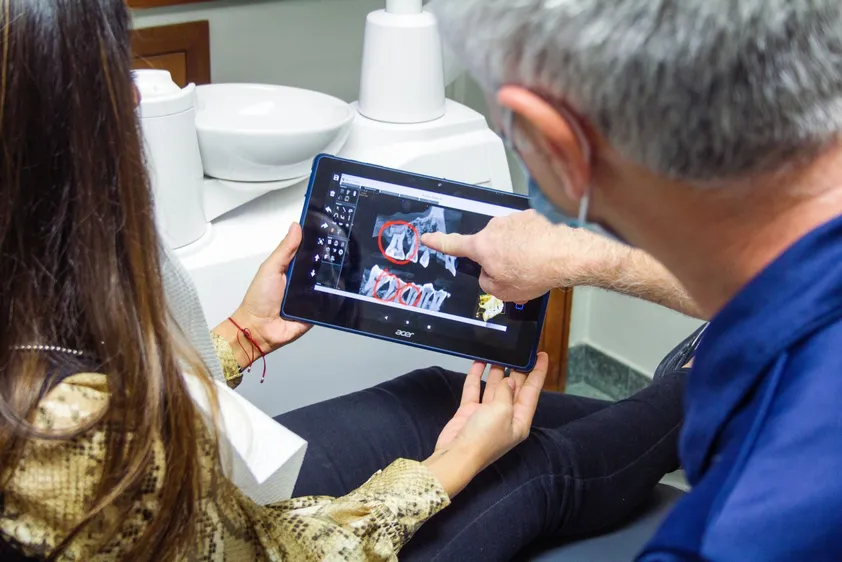 man pointing to X-rays on screen, discussing with female patient, periodontist Muncie, IN periodontics