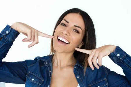 dark haired woman smiling pointing at her teeth, dental veneers Harrisburg, PA cosmetic dentistry