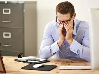 A worn out male rubbing his nose bridge