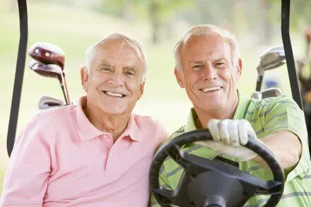 two older men sitting in golf cart smiling, removable dentures Seminole, FL dentist
