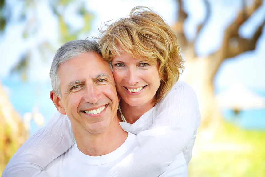 older couple hugging outdoors near ocean, smiling nice teeth, dental bridge Bradenton, FL