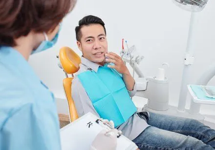 man holding mouth in pain talking to dentist, needs root canal treatment Rocky River, OH dentist