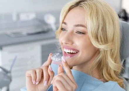 blond woman at dentist, placing clear aligners on teeth, Invisalign Philadelphia, PA dentist