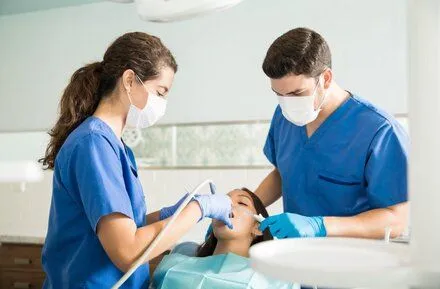 dentist and assistant working on female patient's teeth, dental fillings Cary, NC dentist