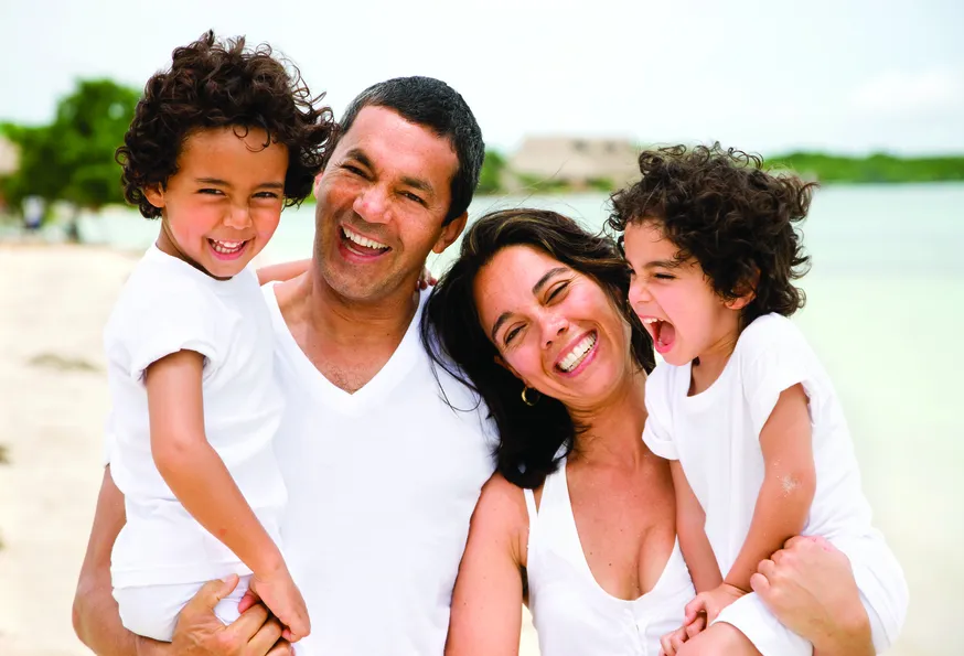 young mom and dad with kids on beach, laughing and smiling, Family Dentist Columbia, MO