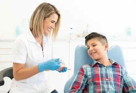 female orthodontist showing boy model of teeth with braces, orthodontist Melrose, MA orthodontics