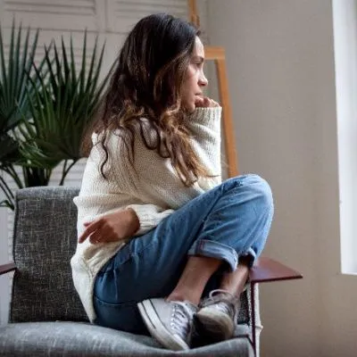 Anxious Woman Sitting in Chair Looking Out a Window