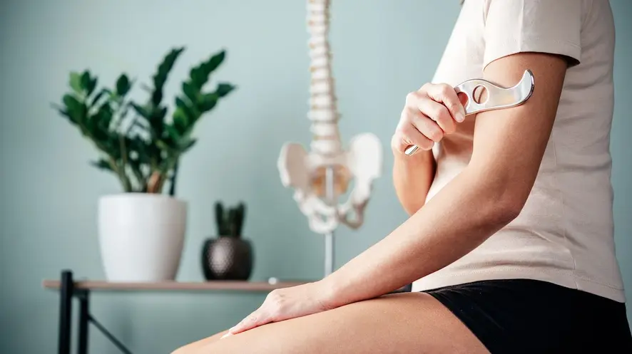 Woman using IASTM method to massage her arms.