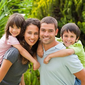 Family of four smiling and posing outside