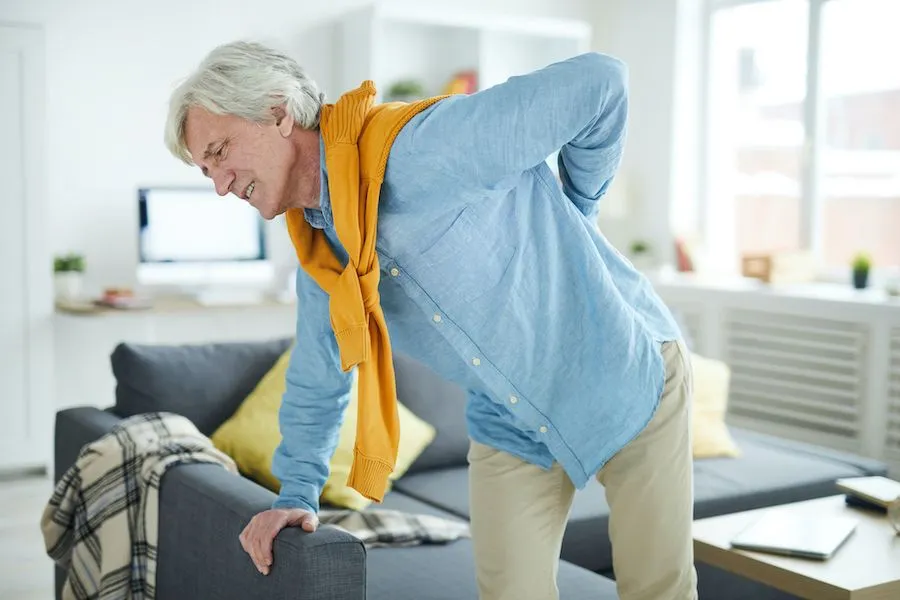 elderly man holding his back due to pain