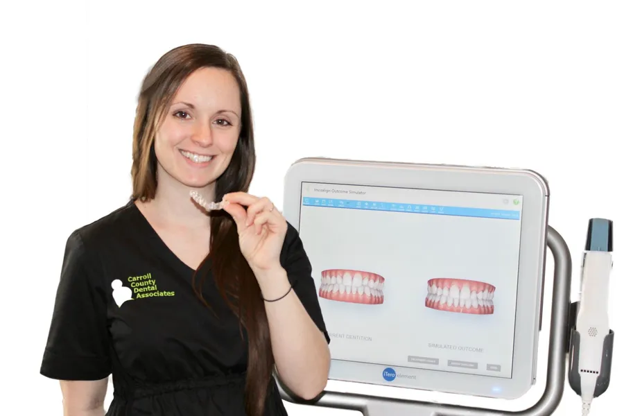 female Carroll County Dental Associates staff member holding Invisalign aligner next to iTero machine, Westminster, MD dentist