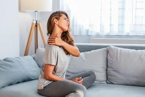 woman with neck pain sitting on couch