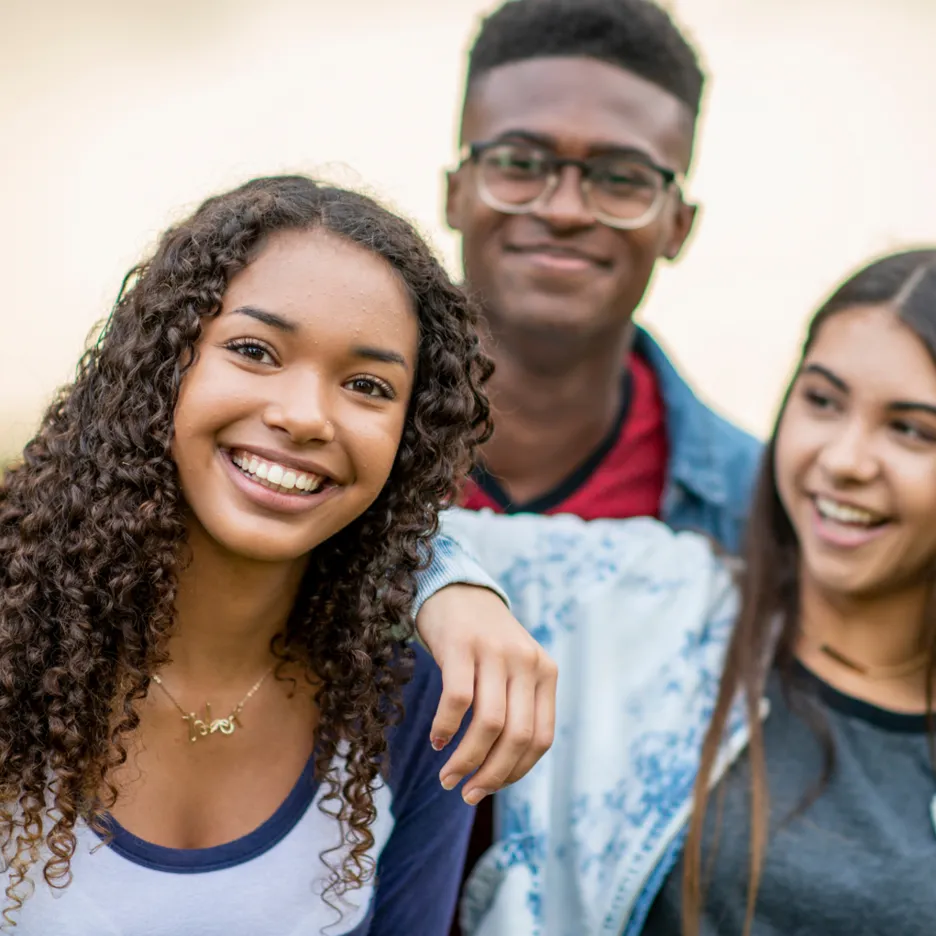 Three young, happy teenagers, smiling and posing together, showing a sense of joy and friendship