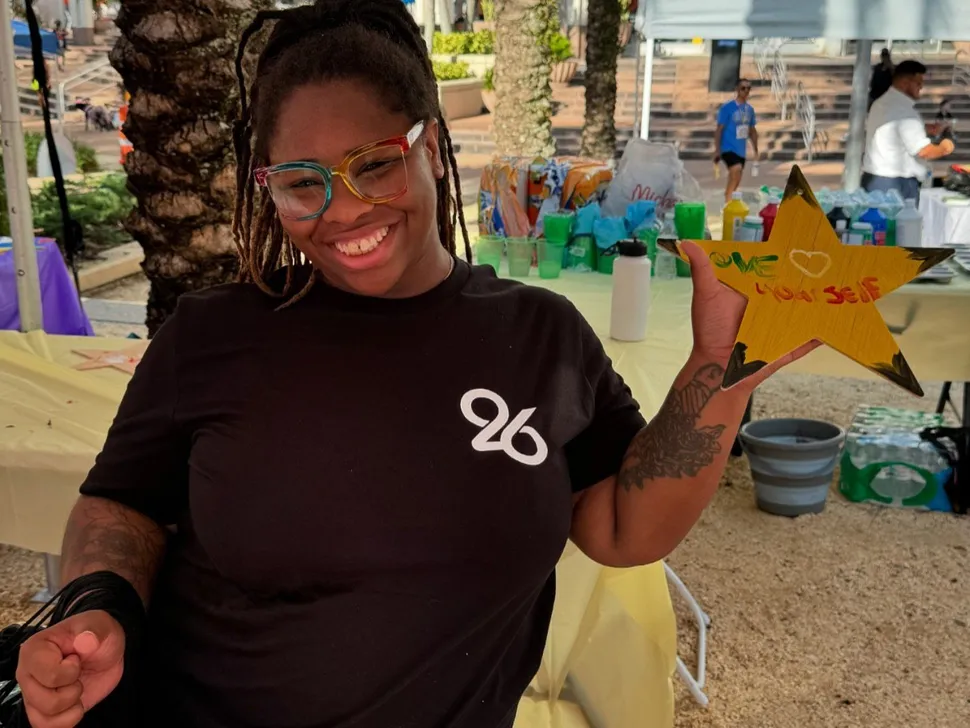 a woman smiling and holding up a colorful painted star