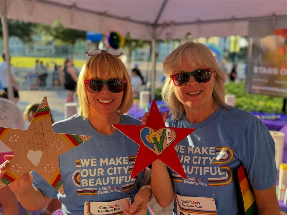 two women holding up painted wooden stars with the word "Love" depicted