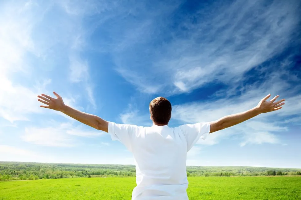 man in field with open arms