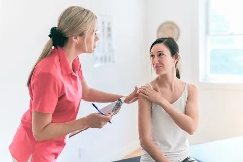 A female client discussing her shoulder pain and personal injury with a chiropractor.