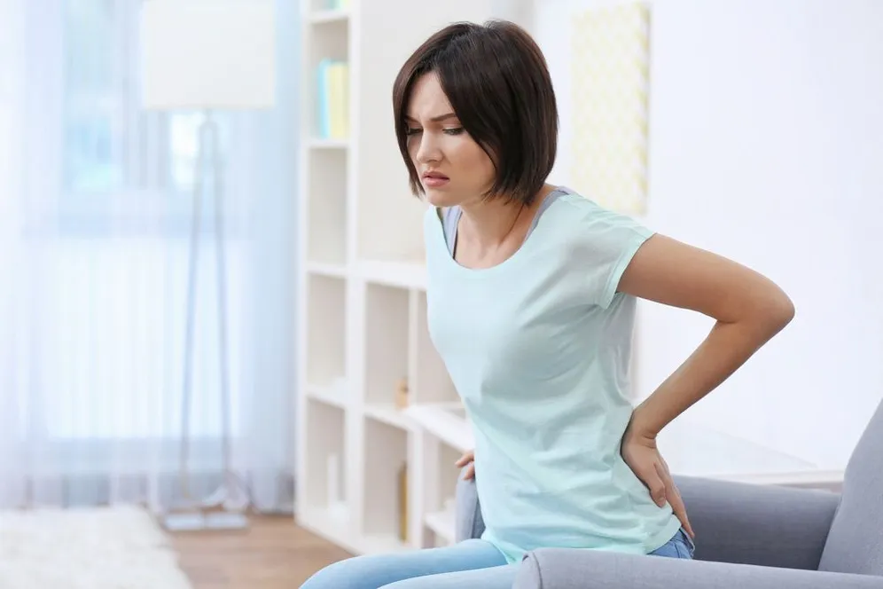 woman sitting holding her back